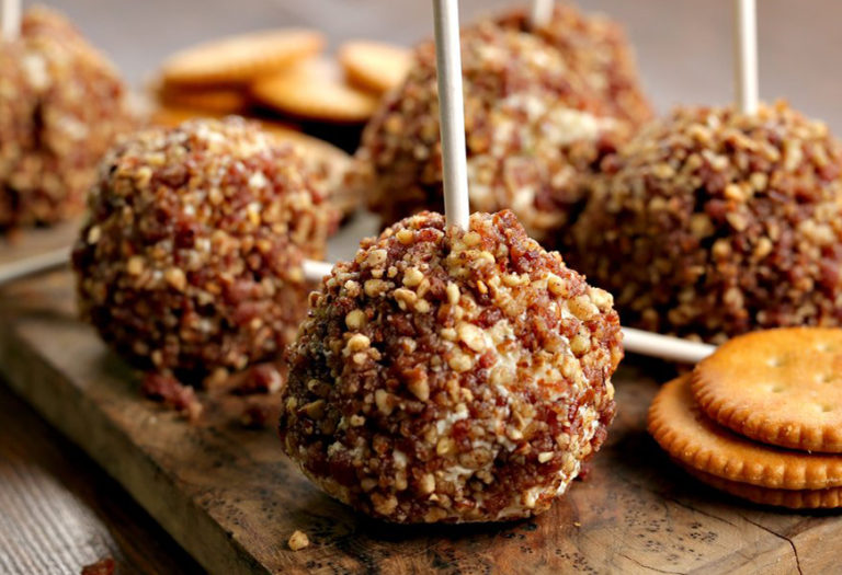 Gourmet cheese ball appetizers coated with nuts and seeds on sticks, served with crackers for wholesale catering and foodservice distribution.