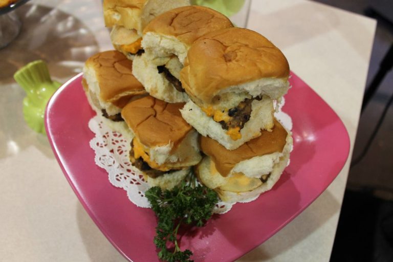 Stack of golden pimento cheese sliders with melted cheese and meat on soft rolls, professionally plated on pink dish with garnish for foodservice.